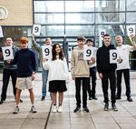 Students holding 9 signs looking happy celebrating their GCSE results